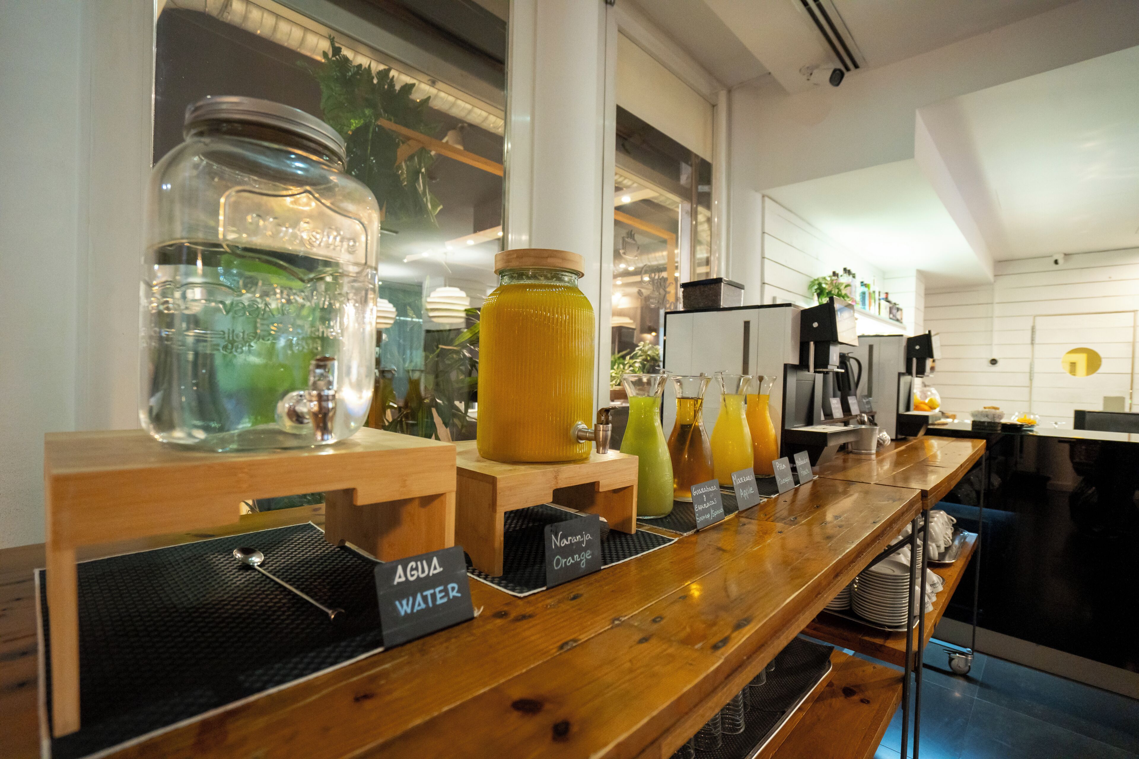 A bar area with a wooden counter, labeled drink dispensers, and a view of the outdoors.