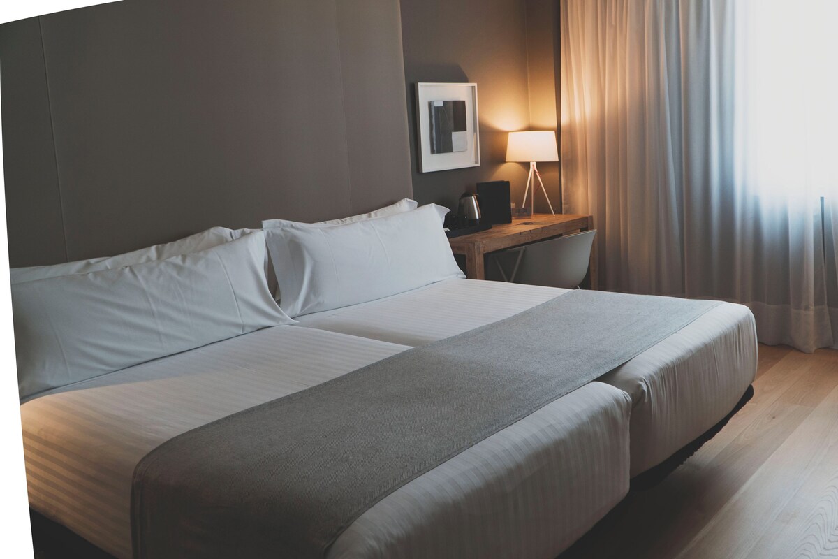 Ein Hotelzimmer mit einem großen Bett, einem Schreibtisch, einem Stuhl und einer Lampe.