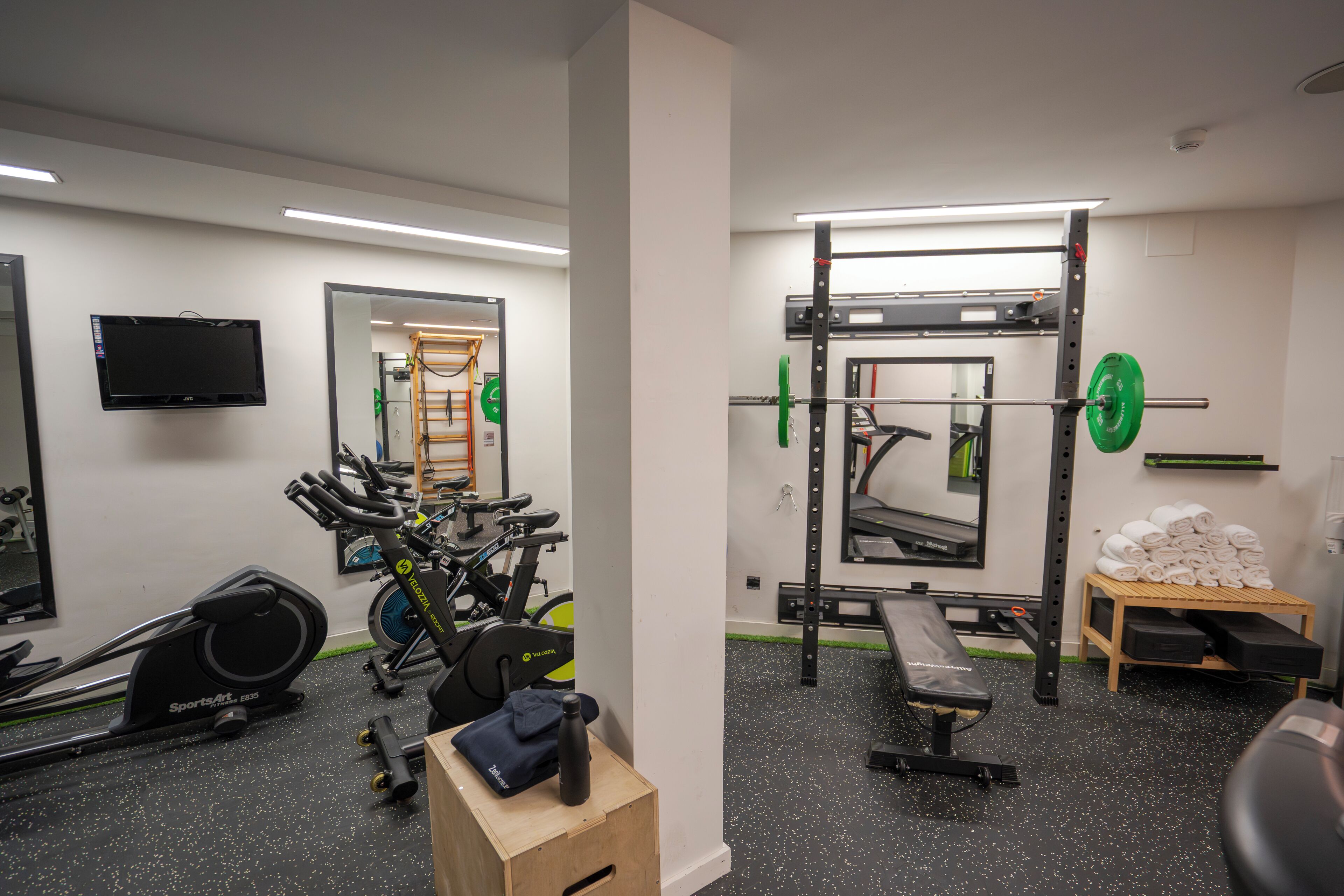 Een sportschool met trainingsapparatuur, een televisie en een spiegel.