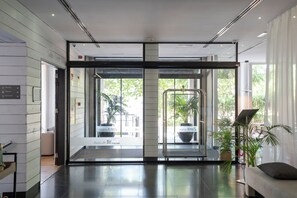 A hotel lobby with a reception desk, glass doors leading to a waiting area, and potted plants. - Hotel Zenit Conde de Orgaz (Madrid)