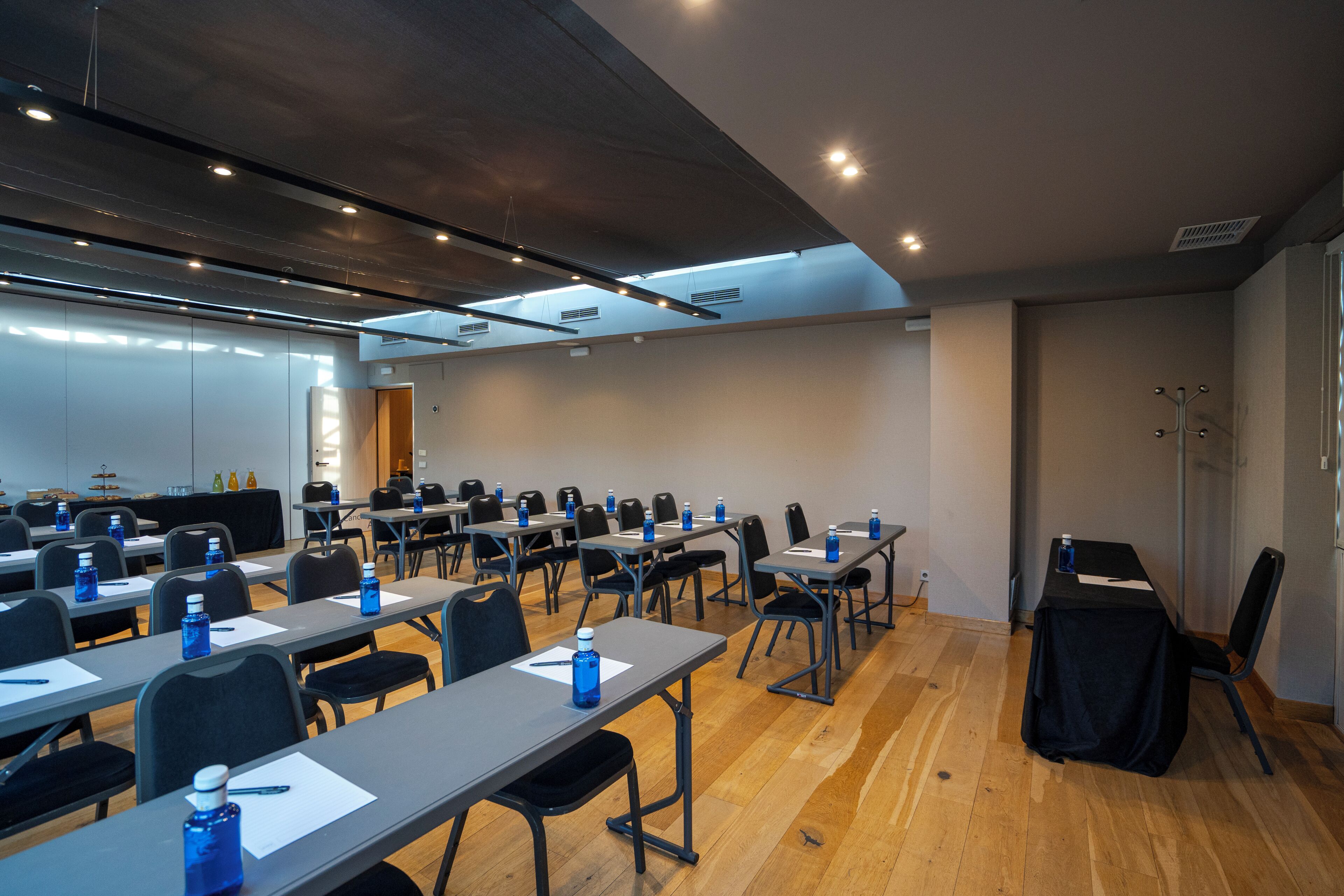 A conference room with multiple tables, chairs, and water bottles.