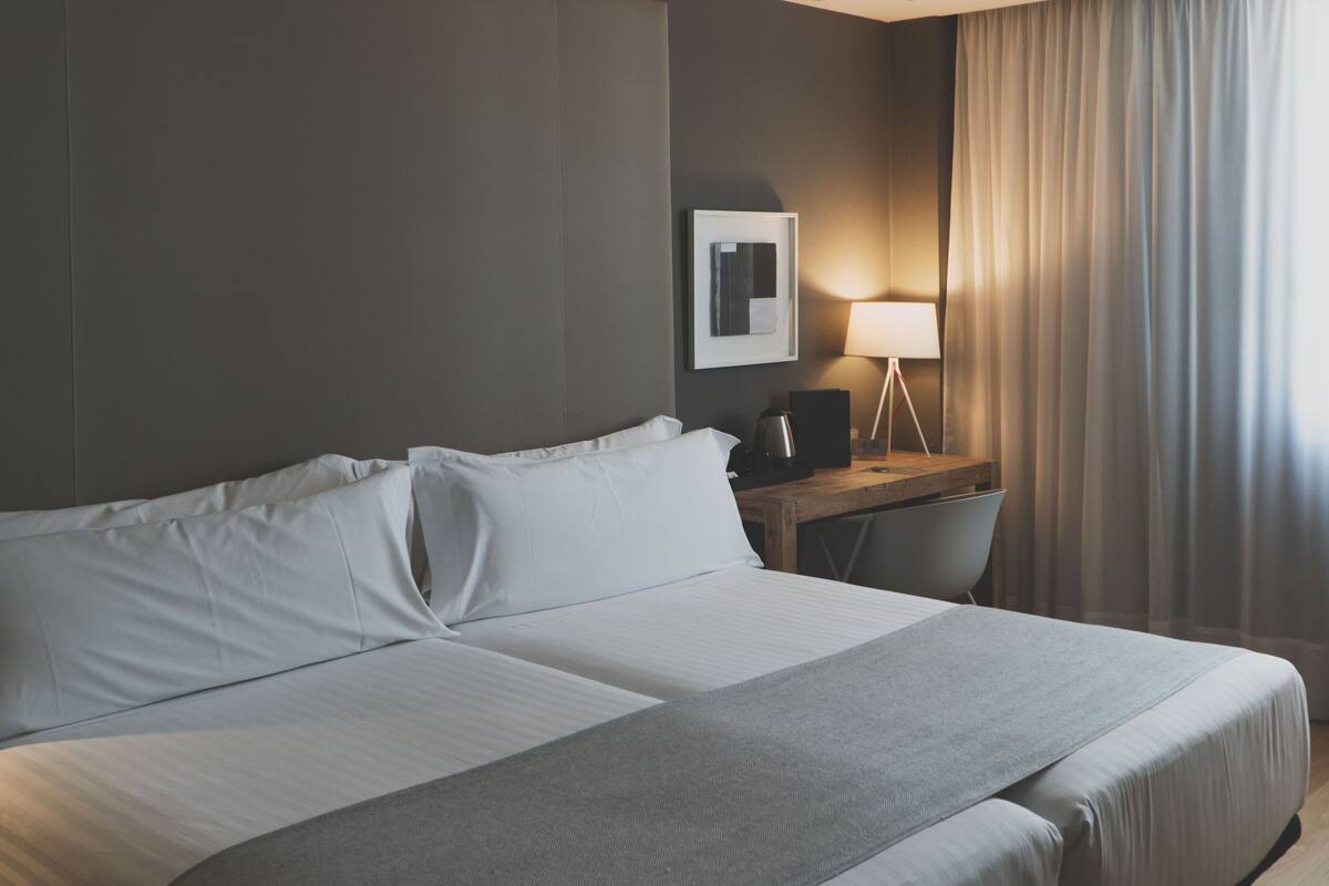 A neatly made bed with white linens in a hotel room.