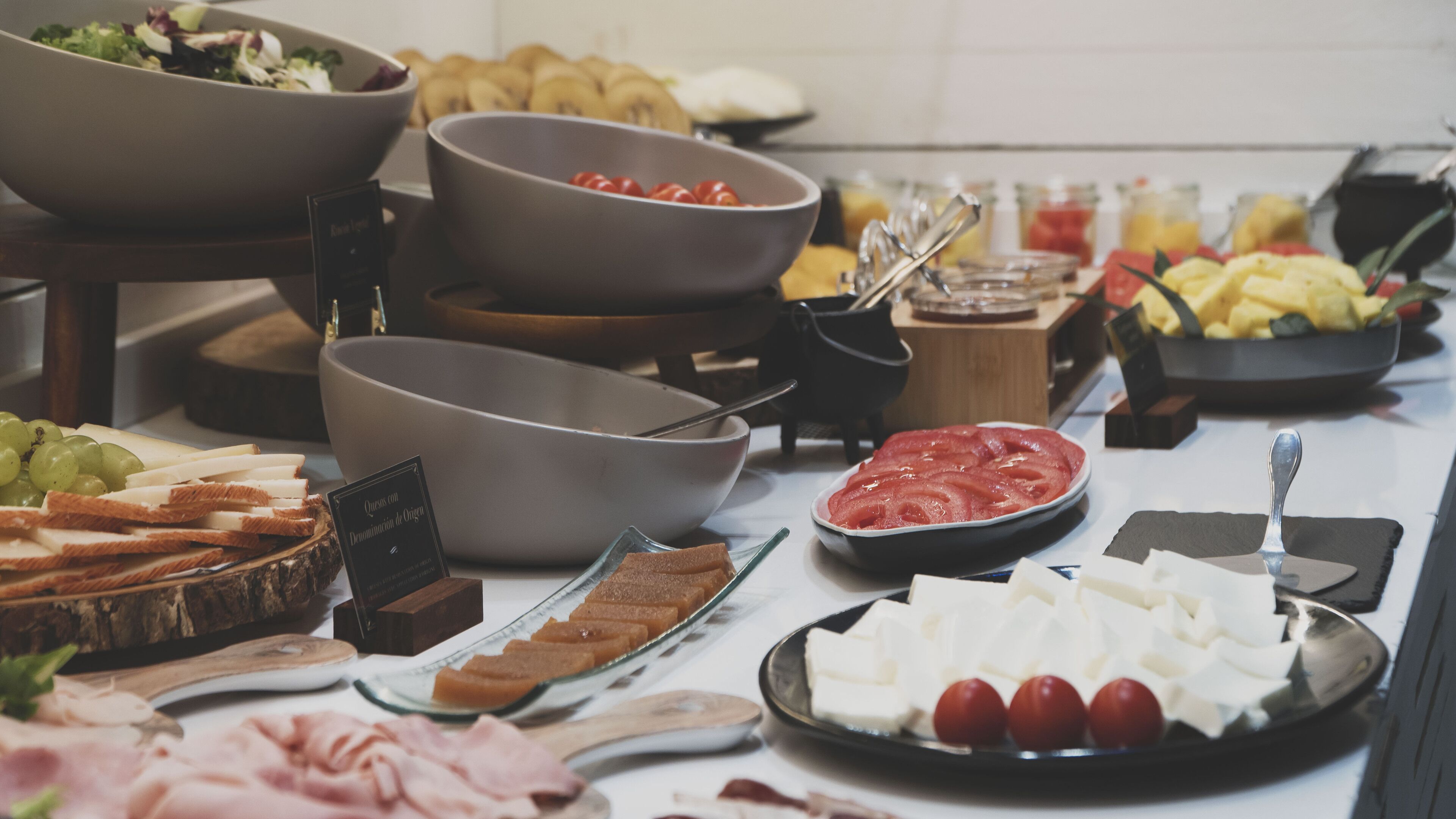 Un bufé con diversos alimentos, incluyendo queso, carnes y frutas.