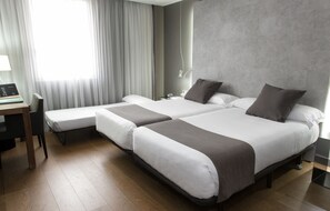 A hotel room with two beds, a desk, and a chair. - Hotel Zenit Conde de Orgaz (Madrid)