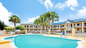 A swimming pool with a white deck, surrounded by a white fence and palm trees. - Days Inn by Wyndham Kingsland Naval Base I-95 (Kingsland)