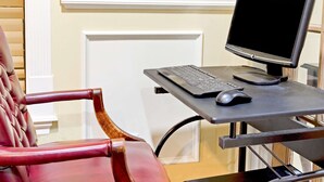 A room with a red leather chair, a small desk with a computer and mouse, and a white door. - Days Inn by Wyndham Kingsland Naval Base I-95 (Kingsland)