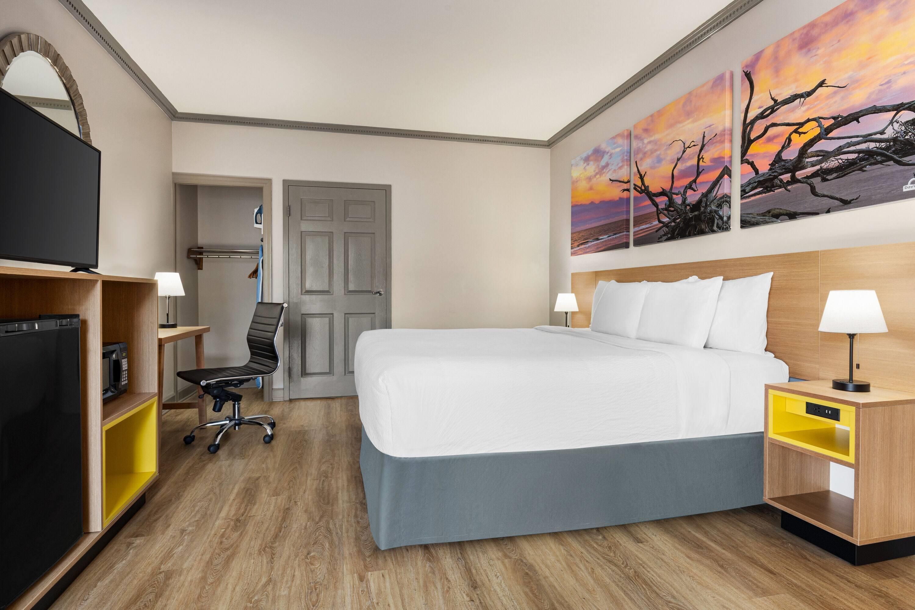 Une chambre d’hôtel avec un lit, un bureau, une chaise, une télévision et un tableau au mur.