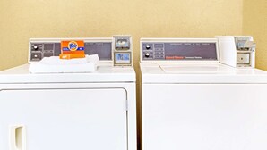 Two front-loading washing machines with Tide detergent and a Speed Queen commercial washer. - Days Inn by Wyndham Kingsland Naval Base I-95 (Kingsland)