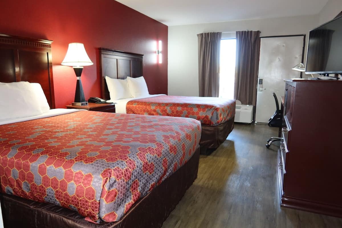 Een hotelkamer met twee bedden, een bureau, een stoel, een televisie en een kledingkast.