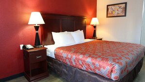 Une chambre d’hôtel avec un lit, deux lampes de chevet, une table de chevet avec un téléphone et un mur rouge.