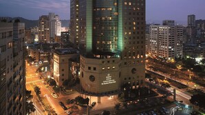 Un hôtel de grande hauteur, doté d’une façade moderne en verre, de nombreux étages et d’une entrée imposante à sa base.