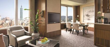 A modern hotel room with a city view, a dining area, and a living room with a flat-screen TV.