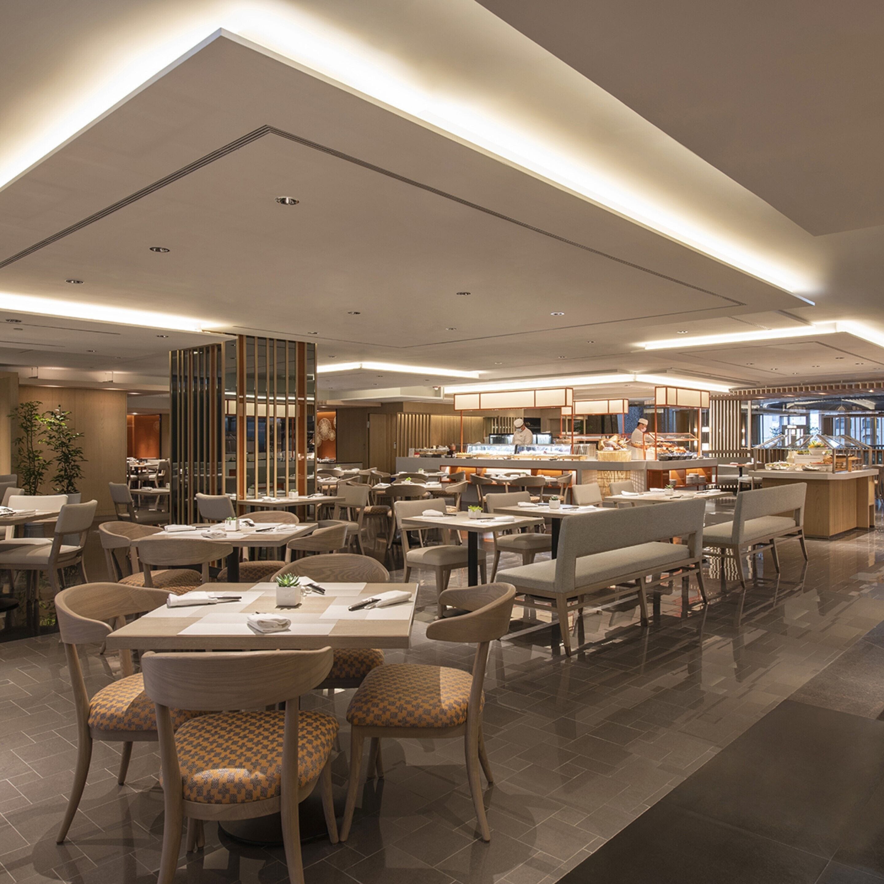 Un restaurante moderno con varias zonas de comedor, incluyendo una barra central y diversas opciones de asientos.