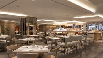 Un restaurante moderno con varias zonas de comedor, incluyendo una barra central y diversas opciones de asientos.