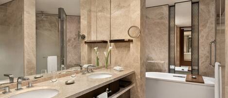 A modern bathroom with two sinks, a bathtub, and a large mirror.