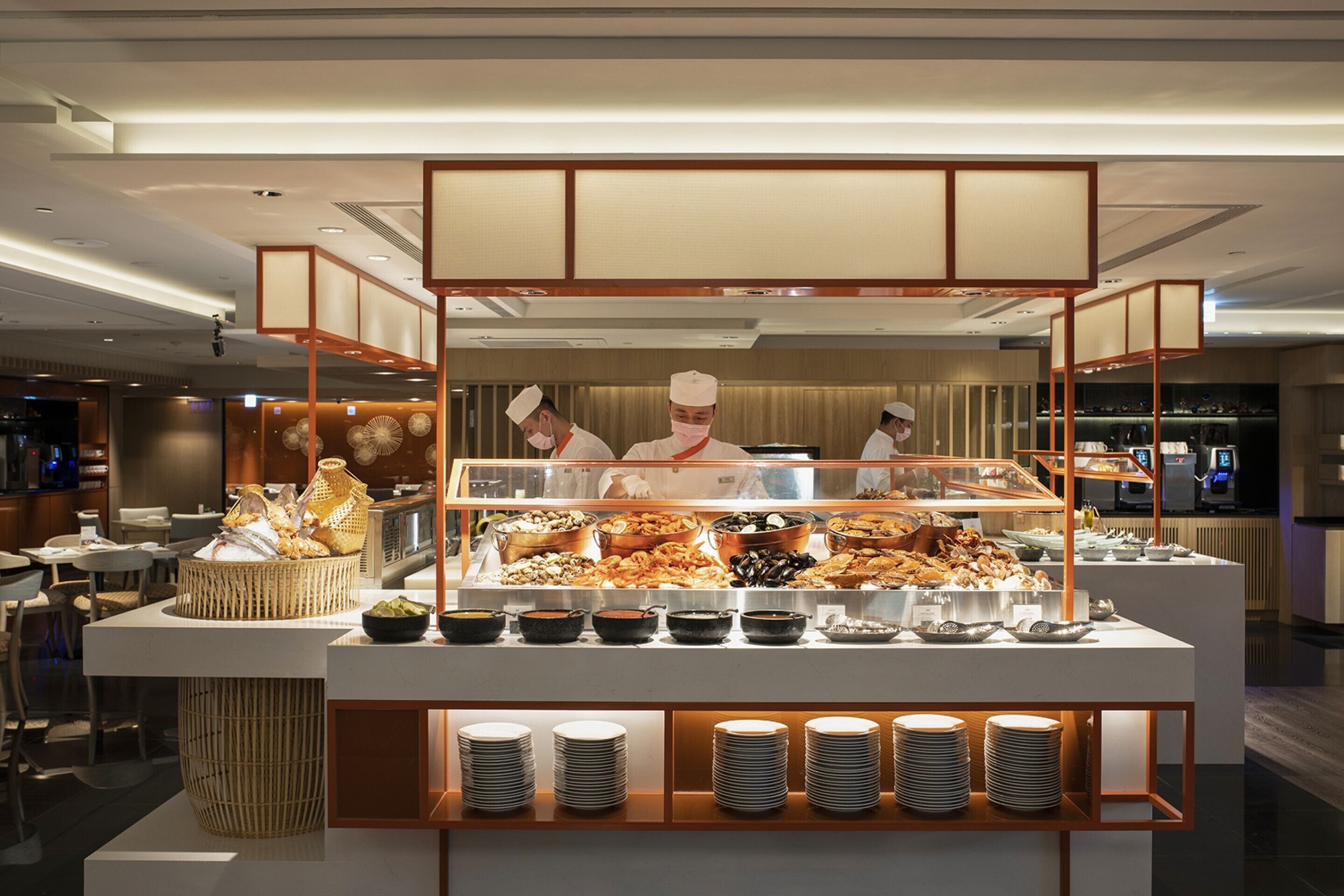 A buffet area with various food items and stacked plates.