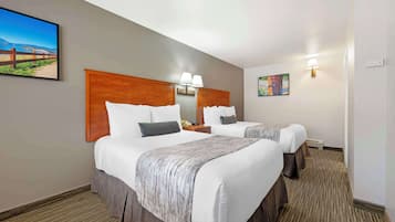 A hotel room with two beds, a wooden headboard, bedside lamps, a telephone, and a painting on the wall.