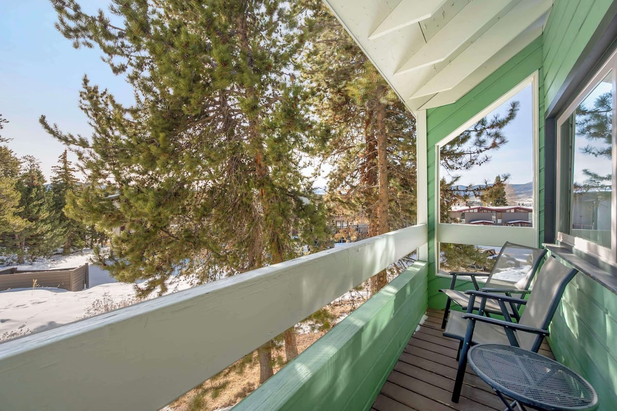 Ein Balkon mit Blick auf hohe Bäume und eine verschneite Landschaft.