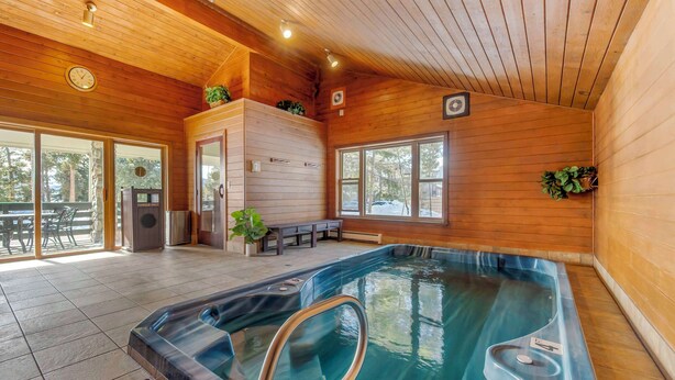 A wooden cabin interior with a hot tub, wooden walls, and large windows. - Best Western Ptarmigan Lodge (Dillon)