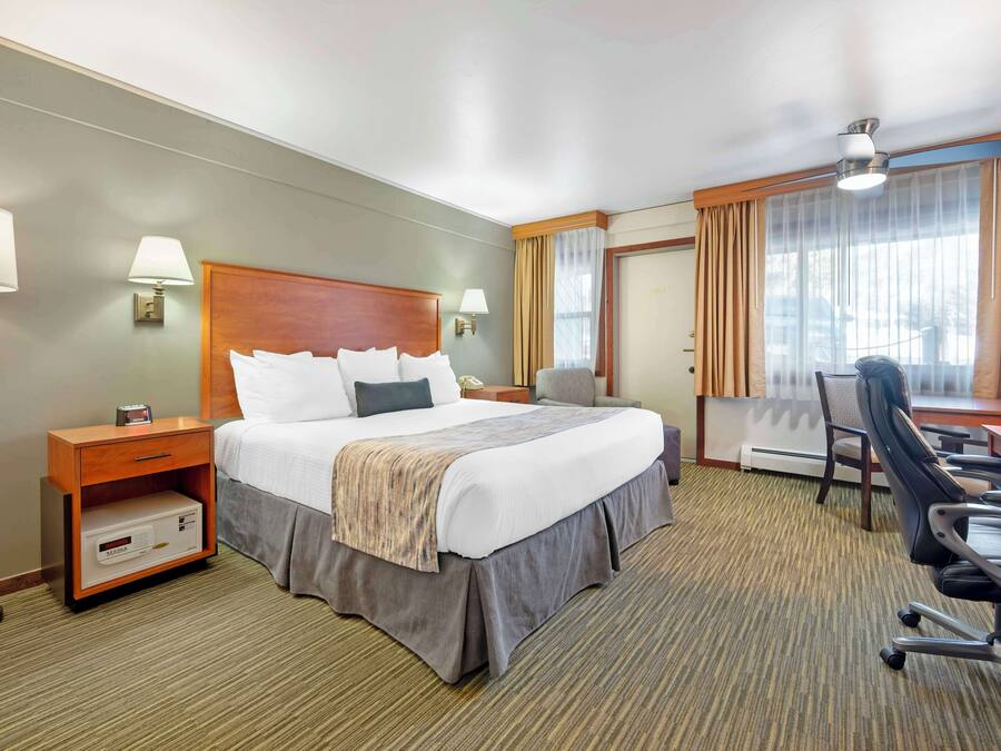 Ein Hotelzimmer mit einem großen Bett, einem Schreibtisch, einem Sessel, einem Nachttisch und einer Lampe.