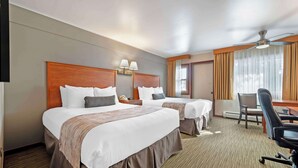 A hotel room with two beds, a desk, a chair, a ceiling fan, and a window with curtains. - Best Western Ptarmigan Lodge (Dillon)