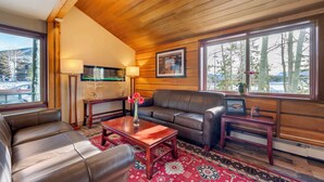 A cozy living room with a wooden ceiling, leather sofa, and a red patterned rug. - Best Western Ptarmigan Lodge (Dillon)