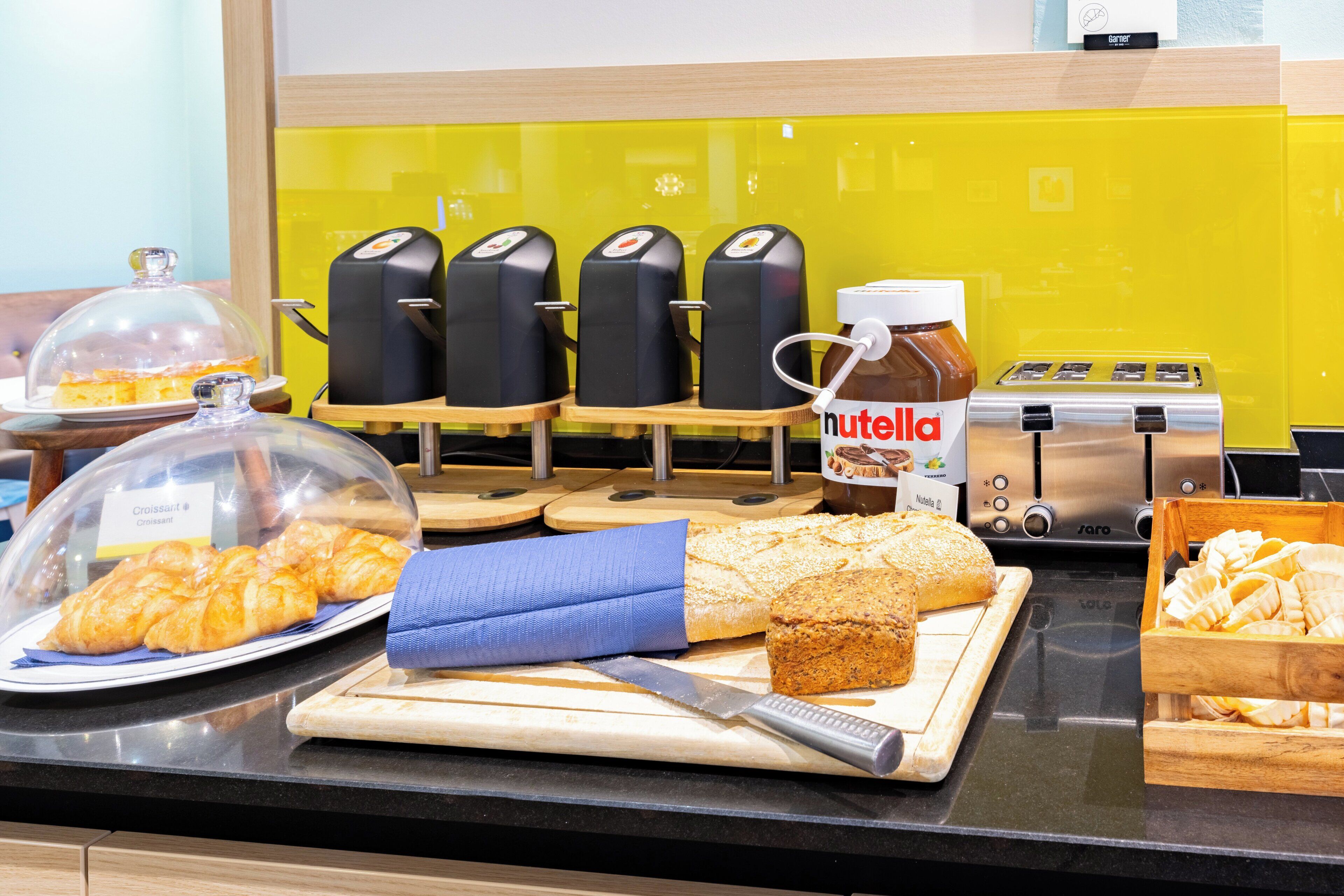 A breakfast buffet with croissants, bread, and Nutella spread.