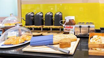 A breakfast buffet with croissants, bread, and Nutella spread.