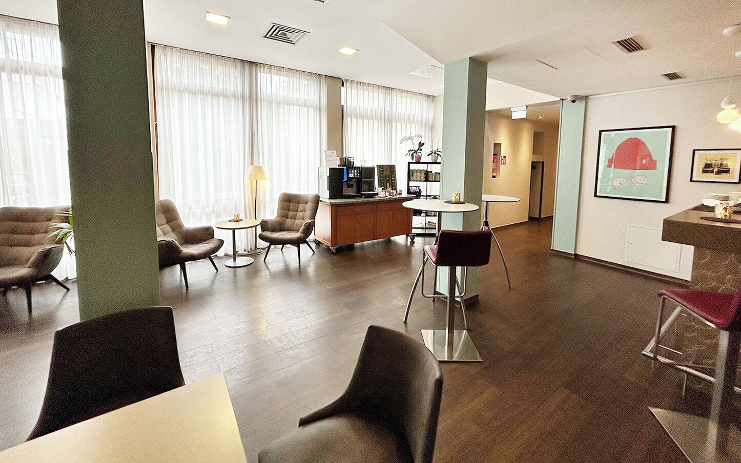 Eine großzügige Hotelhalle mit Rezeption, Sitzgelegenheiten und großen Fenstern.