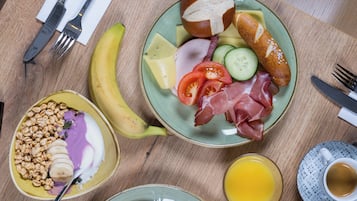 A breakfast setting with plates of food, utensils, and a cup of coffee.