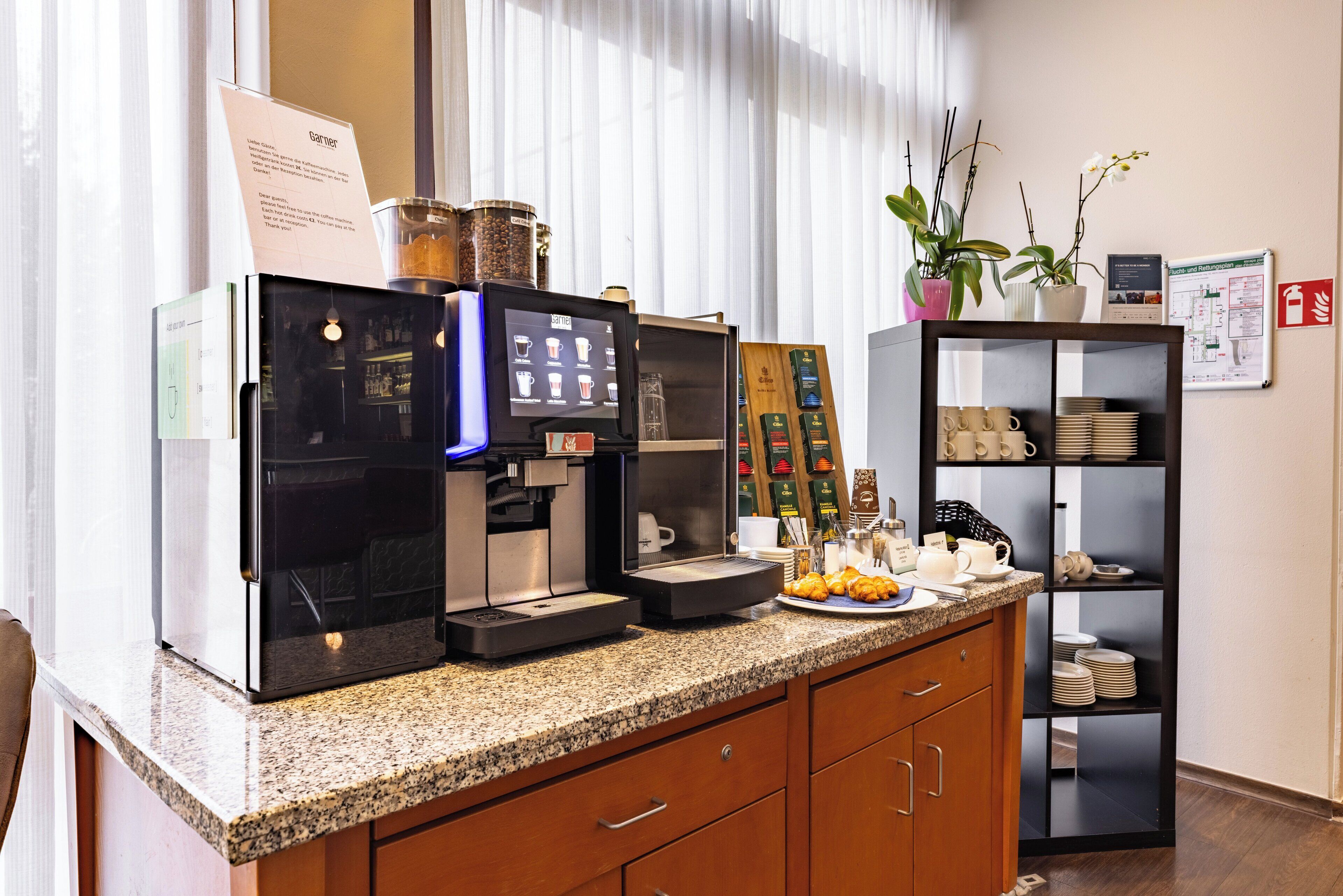 A coffee station with a coffee machine, a menu board, and a shelf with cups and plates.