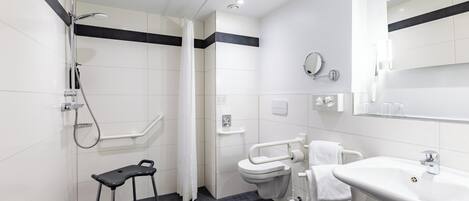 A modern bathroom with a shower, toilet, and sink, featuring a black and white color scheme and a grab bar for accessibility.