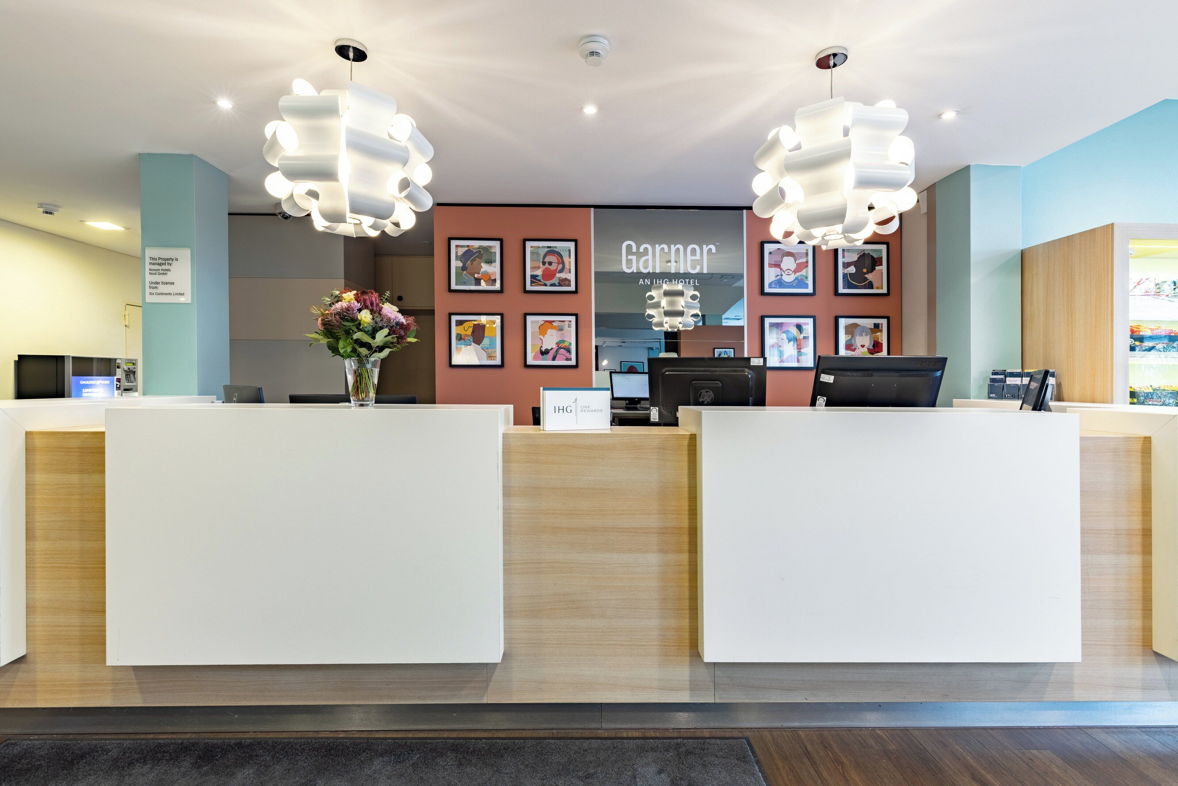 A hotel reception area with two reception desks, a large chandelier, and framed artwork on the wall.