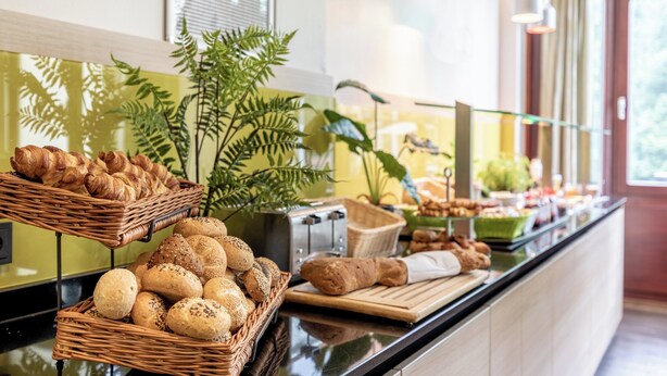 A buffet counter with various breads and pastries. - Garner Hotel Osnabruck by IHG (Osnabrueck)