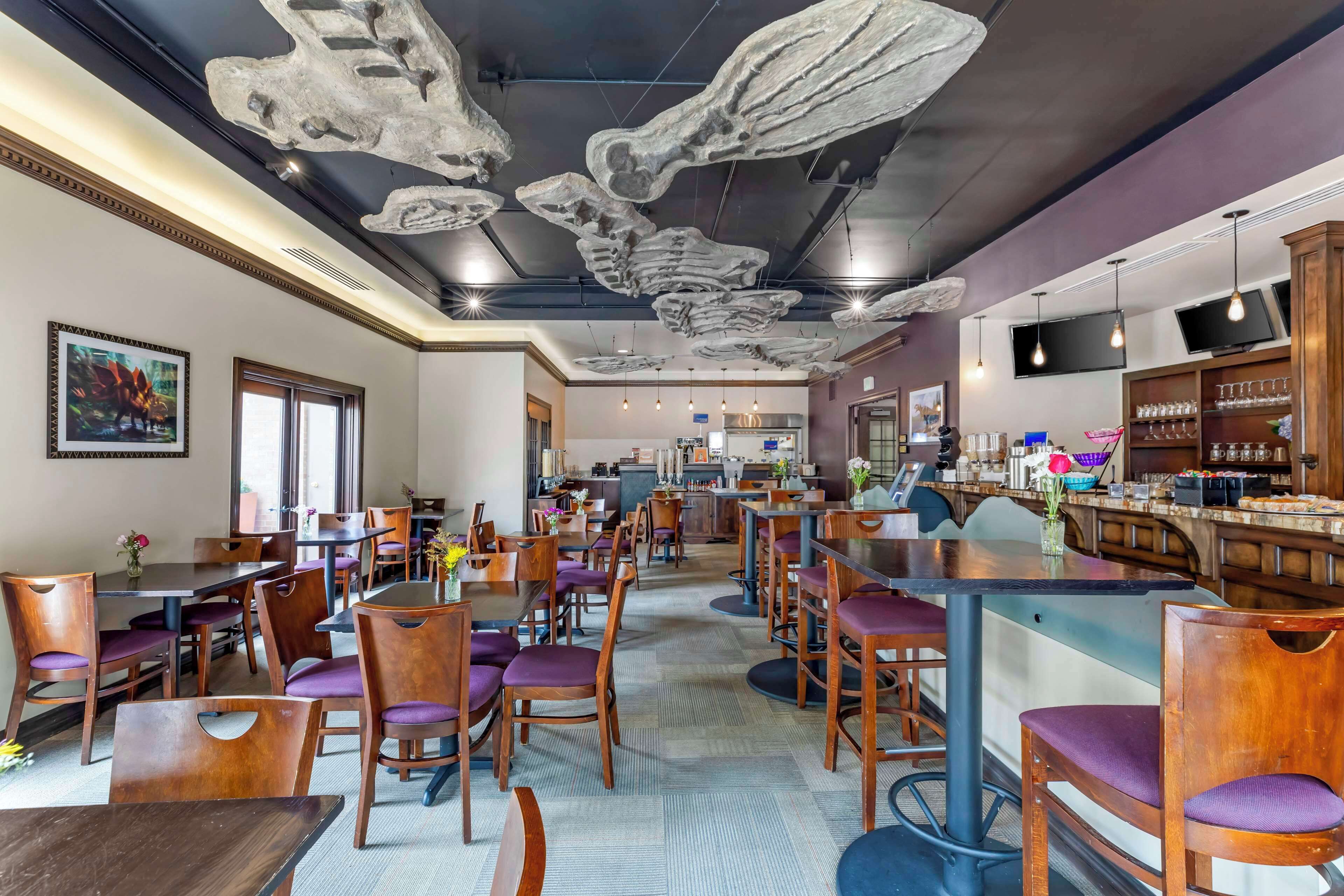A restaurant with wooden tables and chairs, a bar area, and a ceiling with large bone-like decorations.