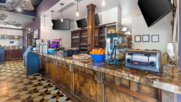 A breakfast bar with a checkered floor, a toaster, and a bowl of oranges. - Best Western Denver Southwest (Lakewood)