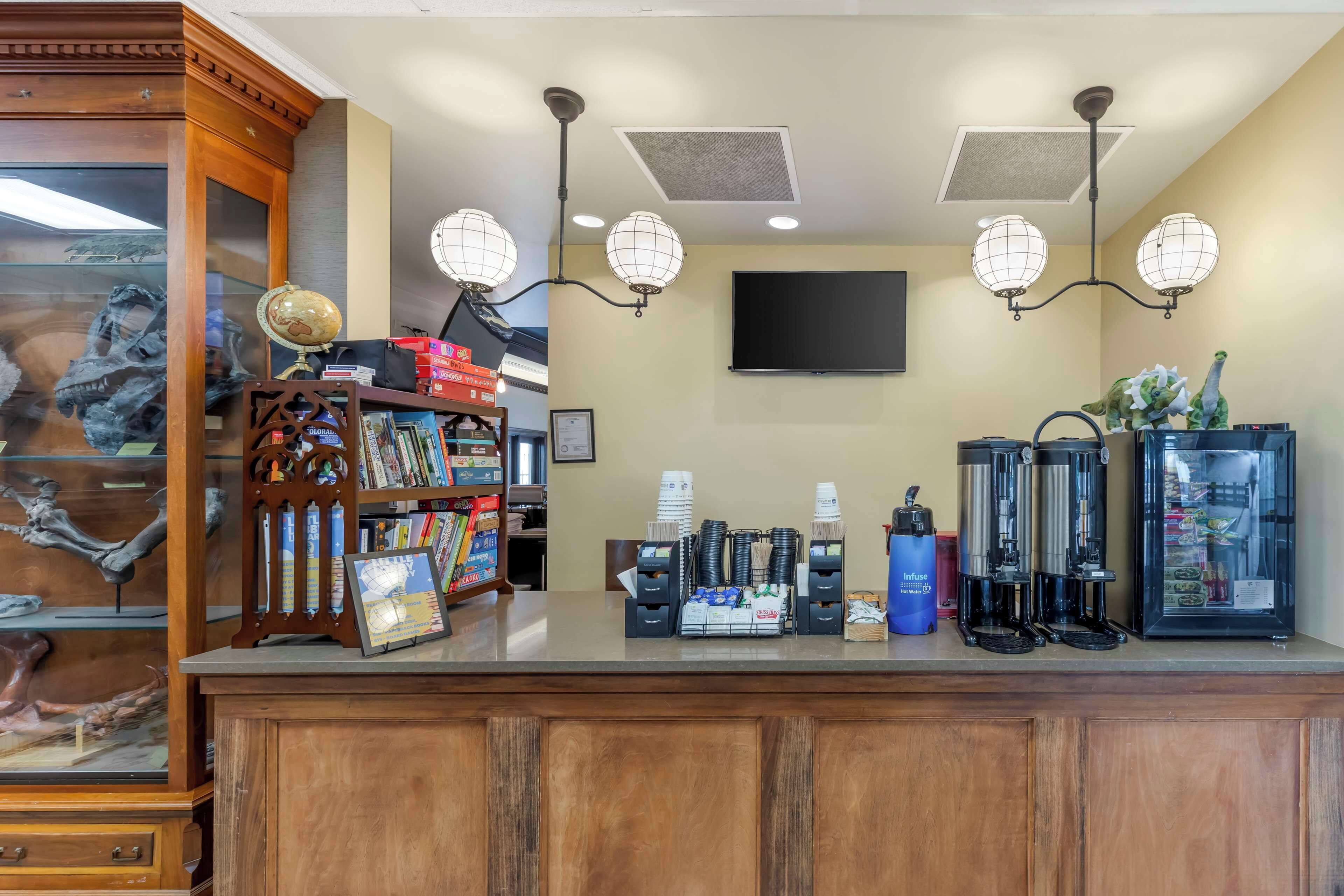 A reception area with a wooden counter, globe lamps, a coffee machine, and a refrigerator.