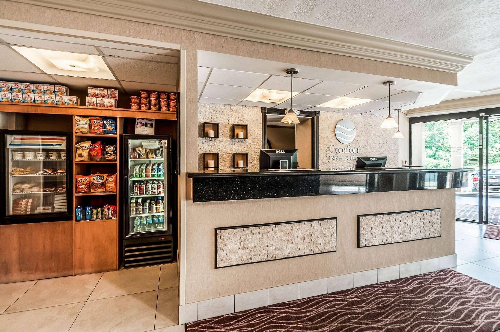 Een hotellobby met een receptiebalie, een snackbar en een koelkast vol drankjes.
