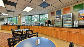 A hotel breakfast area with a counter, seating, and a view of the outdoors.