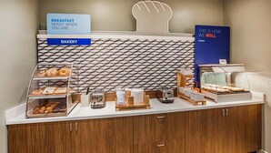 Eine Bäckertheke mit verschiedenen Backwaren, ein Schild weist auf fertiges Frühstück hin und eine Vitrine zeigt Gebäck.