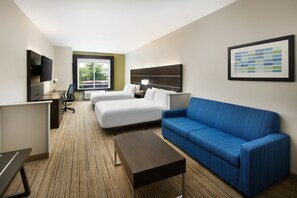 A hotel room with a bed, a blue sofa, a desk with a computer, a TV, and a framed picture on the wall. - Holiday Inn Express & Suites Valdosta West - Mall Area by IHG (Valdosta)