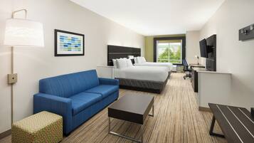A hotel room with a bed, a sofa, a desk, and a TV.