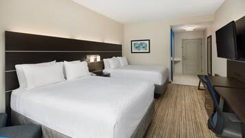 A hotel room with two beds, a desk, a TV, and a bathroom visible through an open door.
