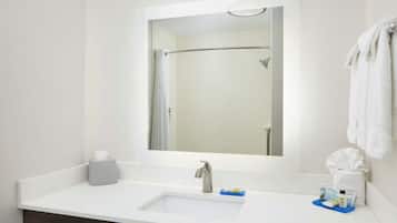A bathroom with a white sink, a mirror, a towel rack, and toiletries on the counter.
