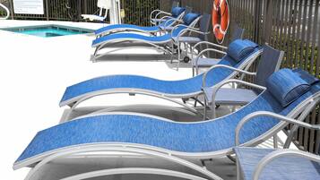 Un área junto a la piscina con sillones de descanso y un flotador.