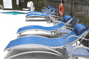 Un área junto a la piscina con sillones de descanso y un flotador.