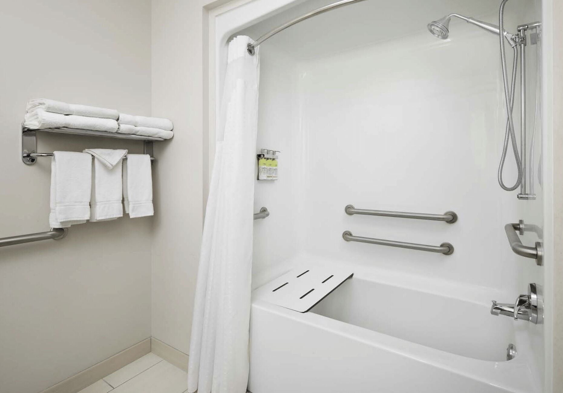 Un baño moderno con bañera, ducha y barras de apoyo.