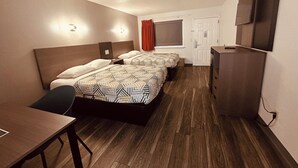 Ein Hotelzimmer mit Bett, Nachttisch, Schreibtisch, Stuhl, Fernseher und Kleiderschrank.