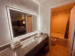 Une salle de bain avec un lavabo, un miroir et des toilettes.