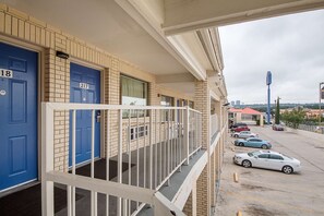 Un immeuble dont les portes sont numérotées, un parking et une vue sur le paysage urbain.